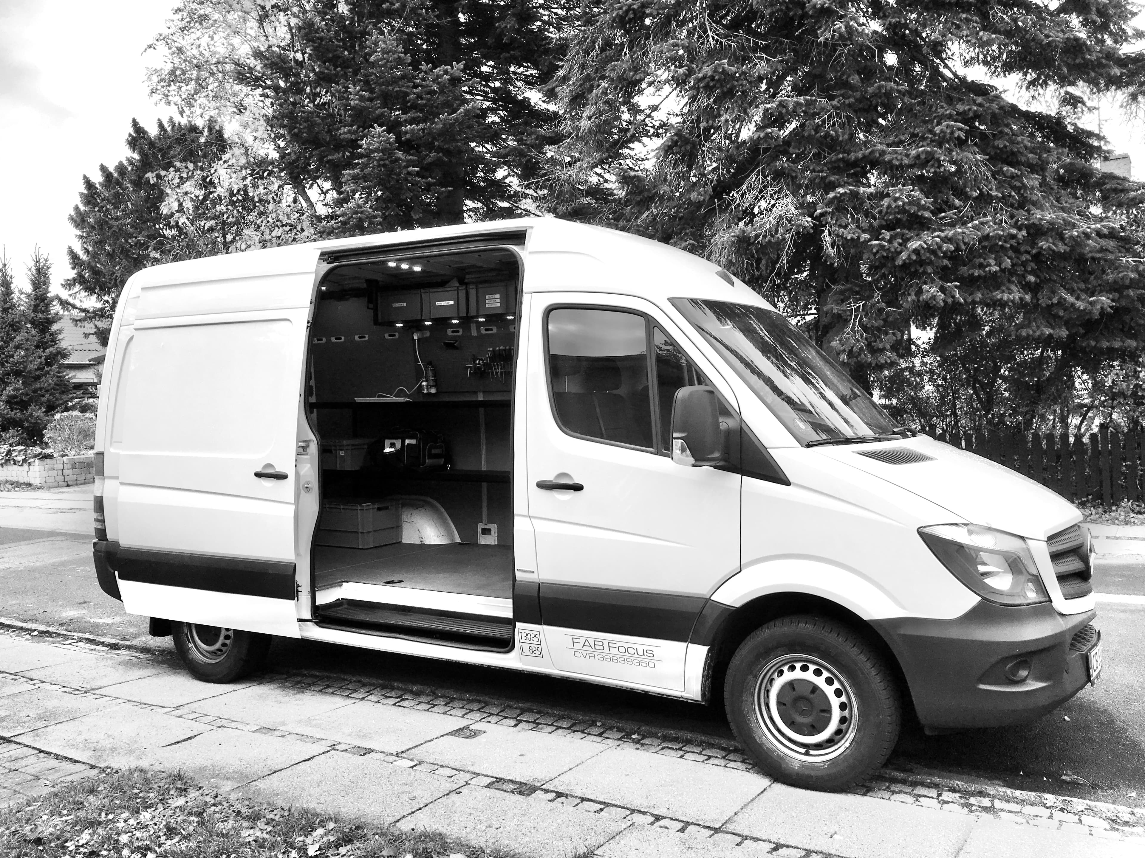 White Mercedes Sprinter van parked with open side door revealing a customized mobile workshop interior.