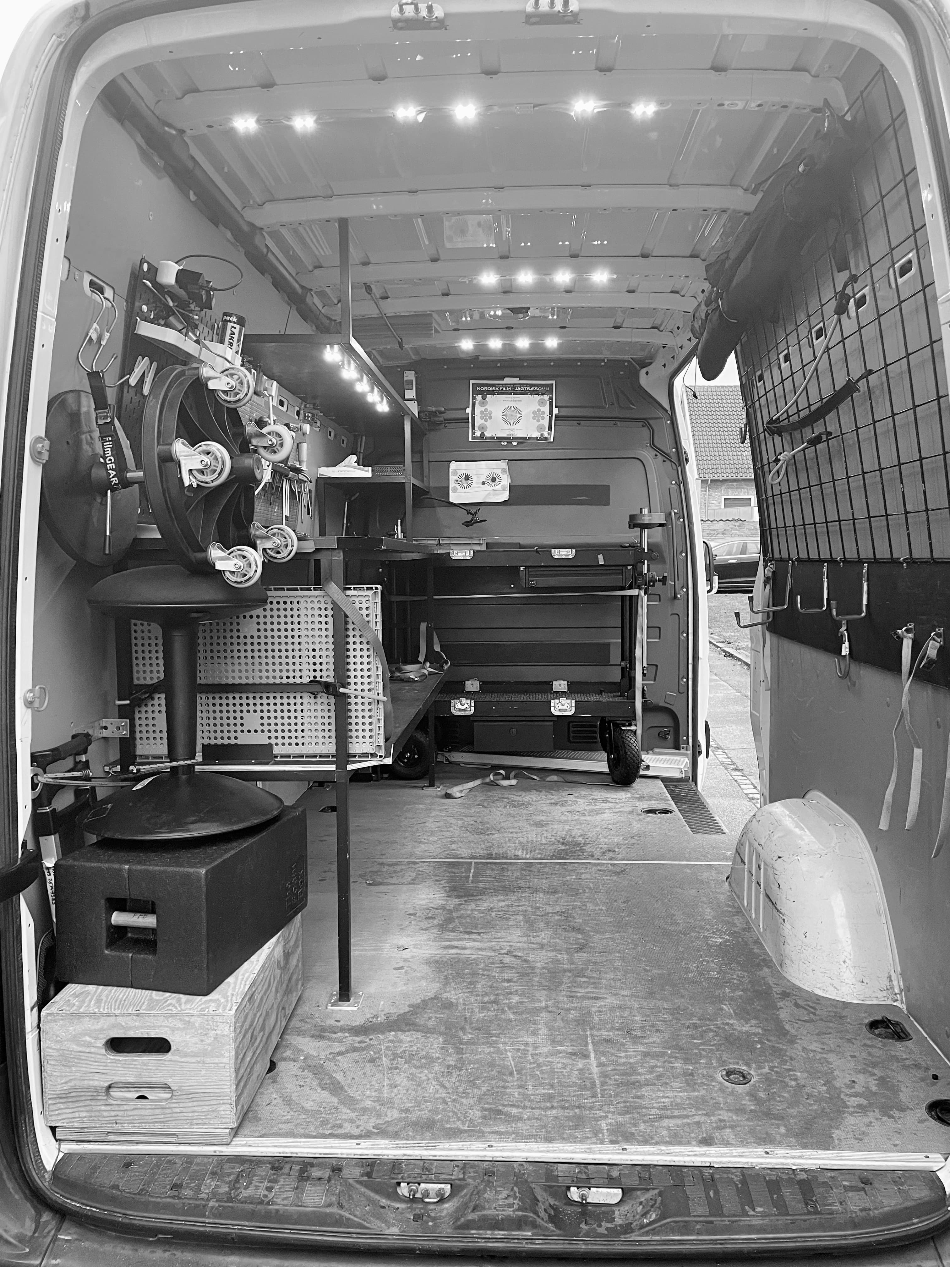 Organized interior of a film production van with equipment, workbenches, and bright LED lighting.